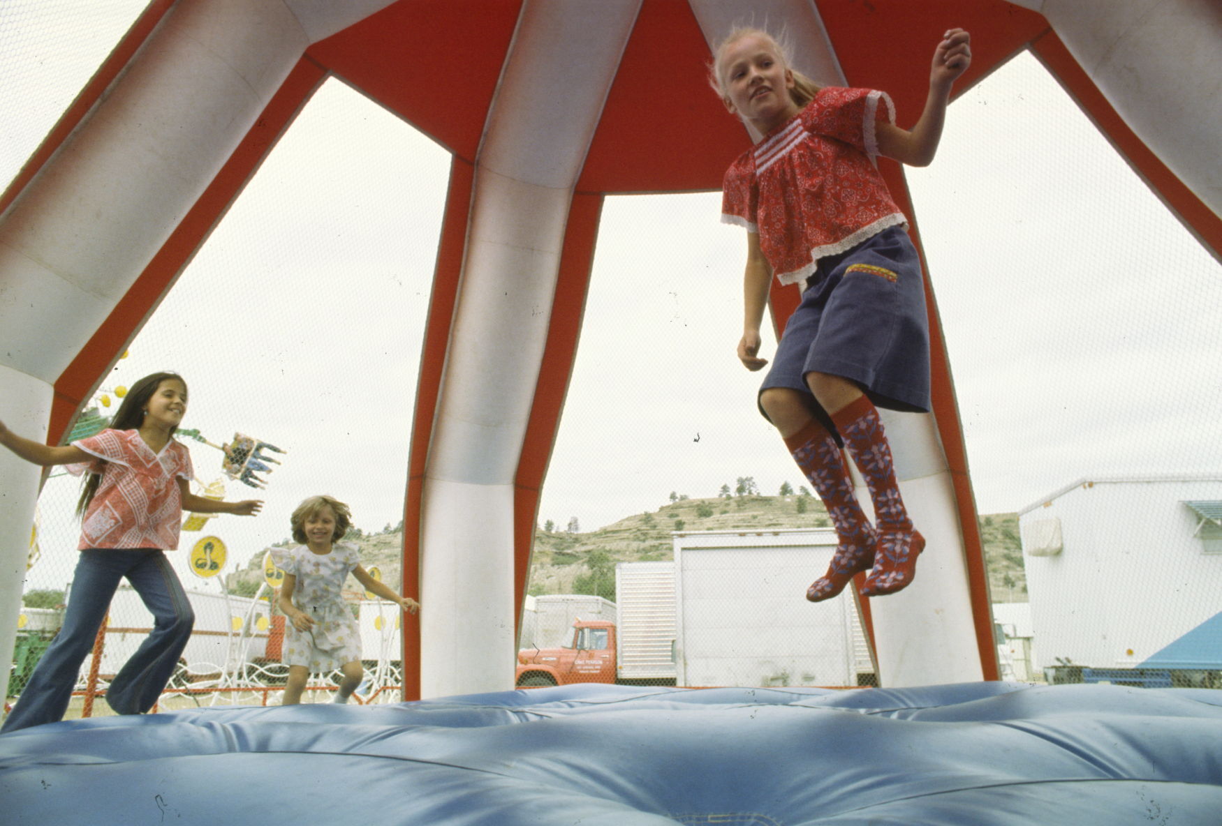 Girls jumping on inflatable trampoline, 1977
